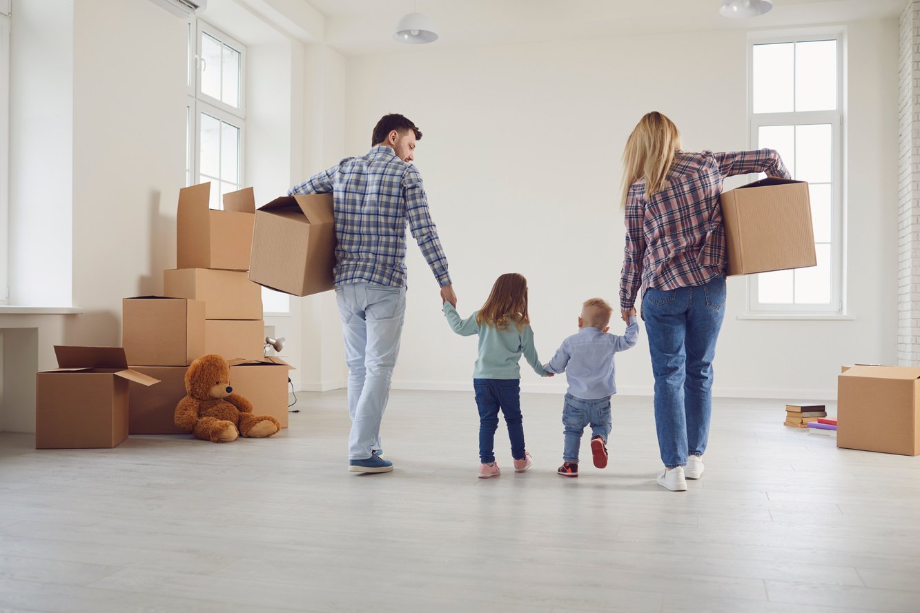 Happy Family with Children Moving with Boxes in a New Apartment House.